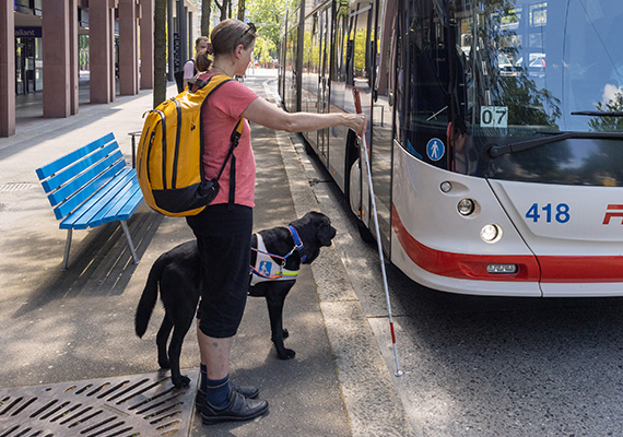 TWS 2026_03_blinde Frau wartet auf den Bus und signalisiert mit dem Weissen Stock
