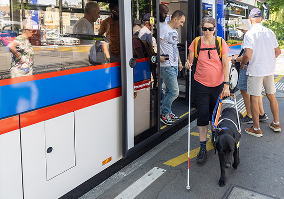 TWS 2026_04_blinde Frau steigt mit Weissem Stock und ihrem Begleithund aus dem Bus