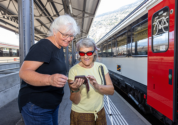 TWS 2026_08_blinde Frau schaut mit einer O+M-Fachfrau auf dem Handy die Zugverbindungen an