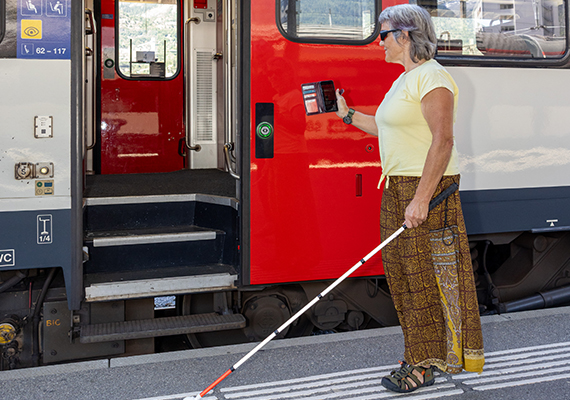 TWS 2026_11_blinde Frau hält ihr Handy bei der Zugtür hin